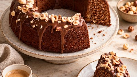 Đanduja torta (Torta Gianduia) sa čokoladnim prelivom i pečenim lešnicima, servirana uz šoljicu espresa.