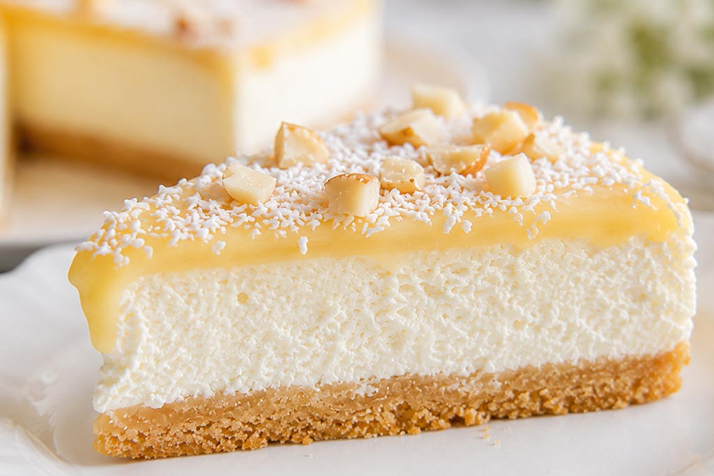 Krupni plan preseka Raffaello torte sa podlogom od keksa, kokos kremom i belim ganašom.